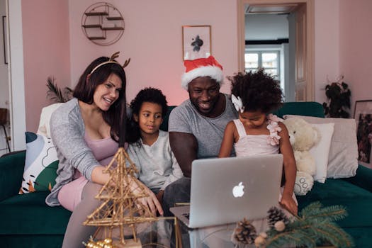 Happy family with children enjoying a Christmas video call at home with festive decorations and a laptop.