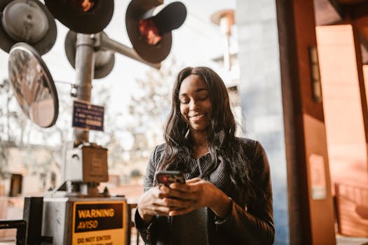 Woman happily using her smartphone outdoors near railway signals, capturing a moment of leisure and connectivity.