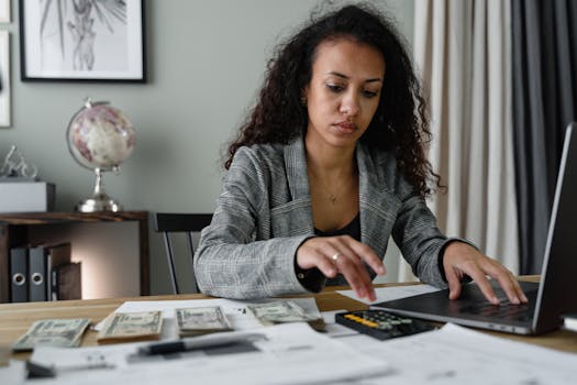 Professional woman analyzing financial documents and counting cash at office desk.