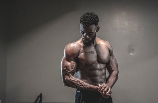 A strong, shirtless male bodybuilder showcasing muscles and strength in a gym setting.